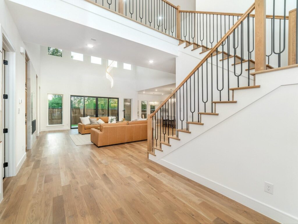 Bright living room with modern staircase and wooden flooring.