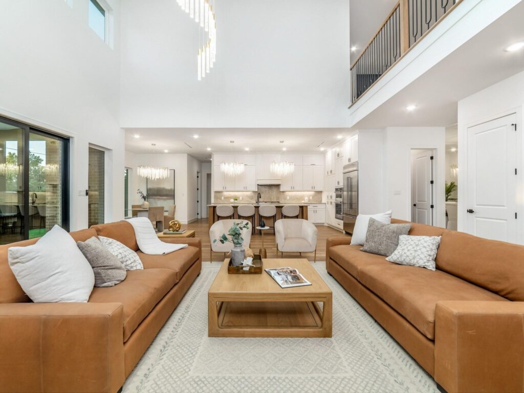 Elegant living room with brown leather sofas and a wooden coffee table under a modern chandelier.