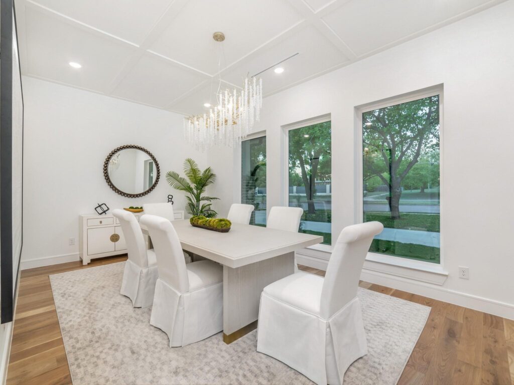 Bright dining room with white chairs and large windows.