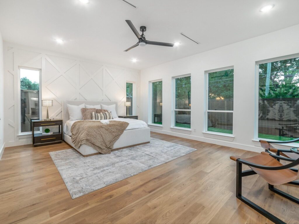 Spacious bedroom with large windows and modern ceiling fan.