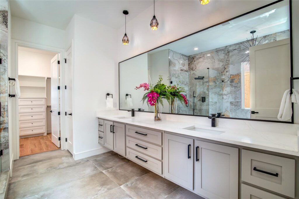 Modern bathroom with double sinks and glass shower enclosure.