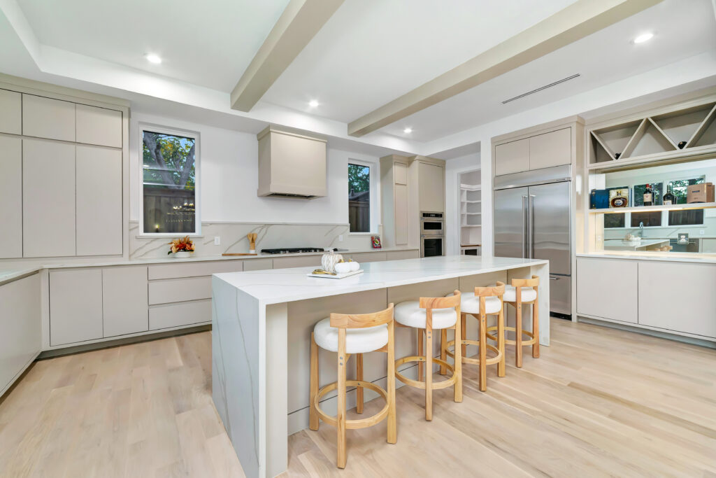 Bright modern kitchen with white island and wooden stools.