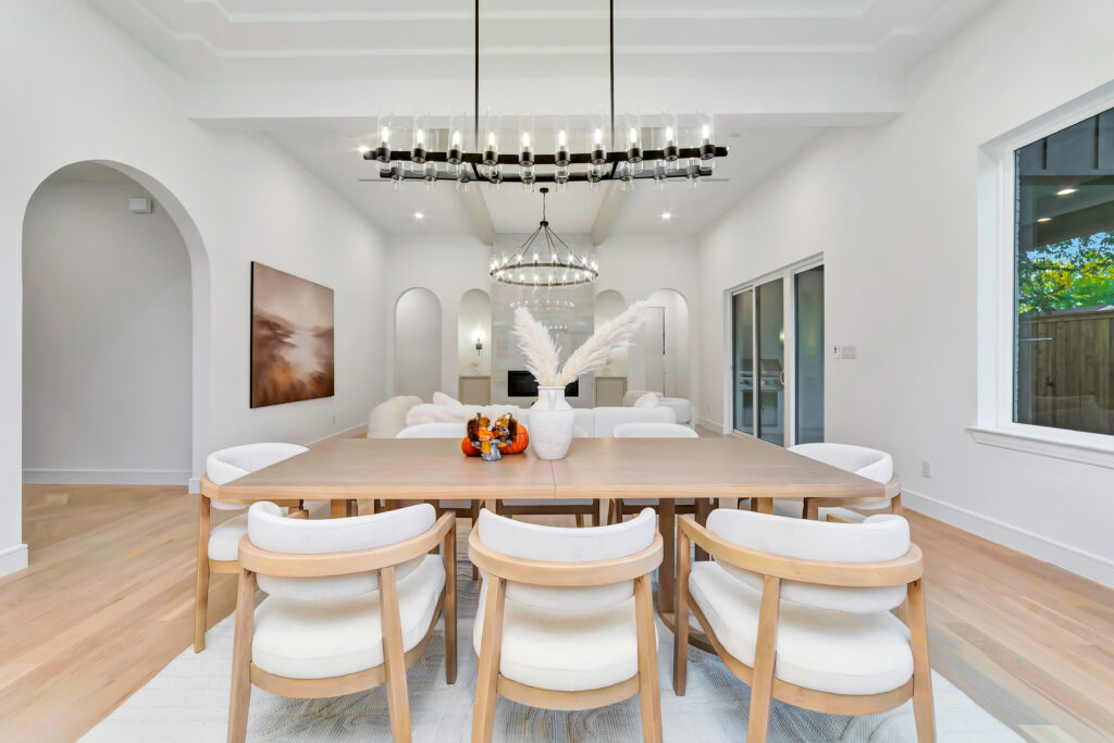 Bright modern dining room with wooden table and white chairs.