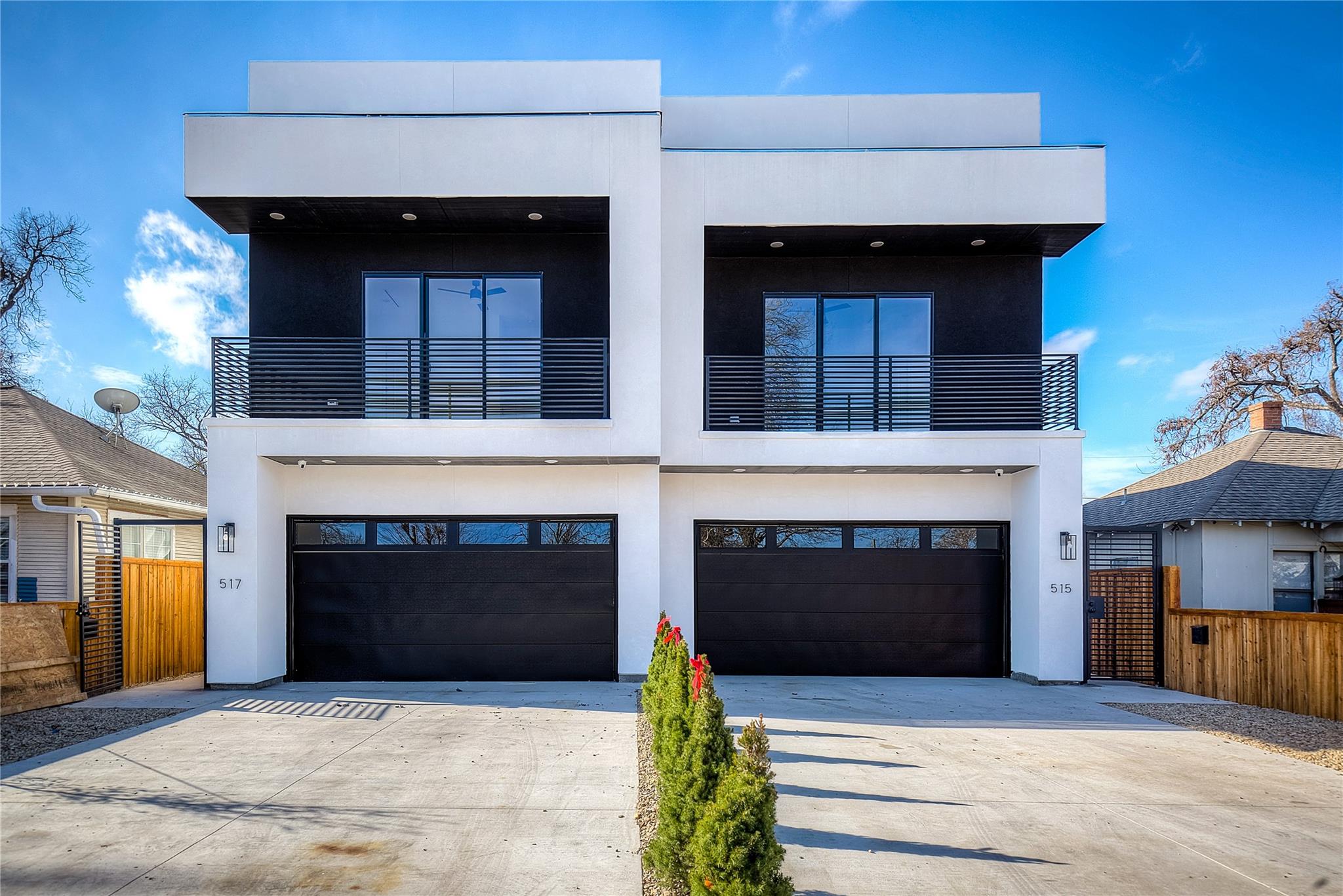 Modern duplex with sleek balconies and double garages under a clear blue sky.