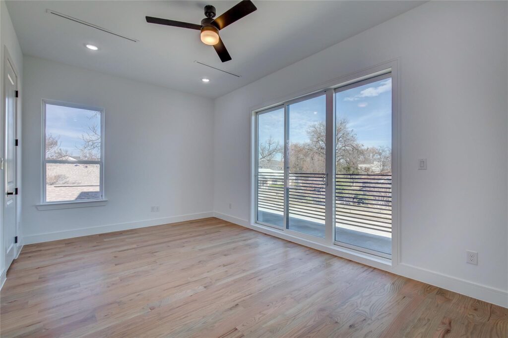 Bright empty room with wooden floor and ceiling fan.