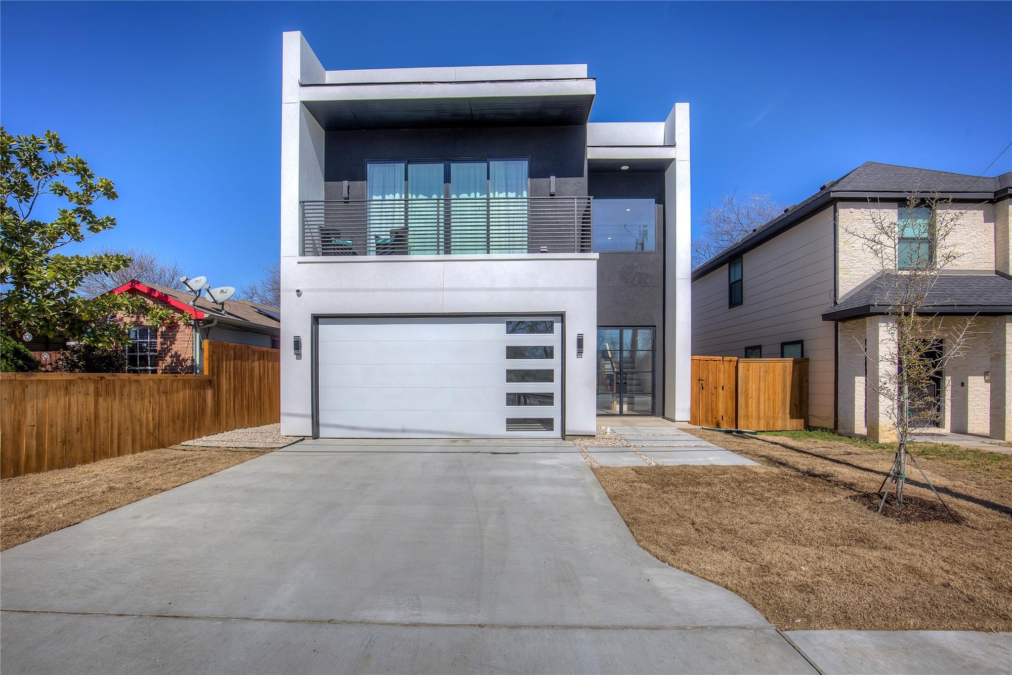 Modern two-story house with large windows and a spacious driveway.