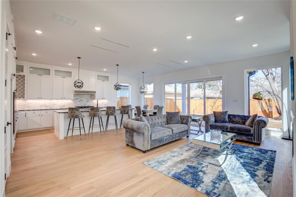 Spacious modern living room with open kitchen and large windows.
