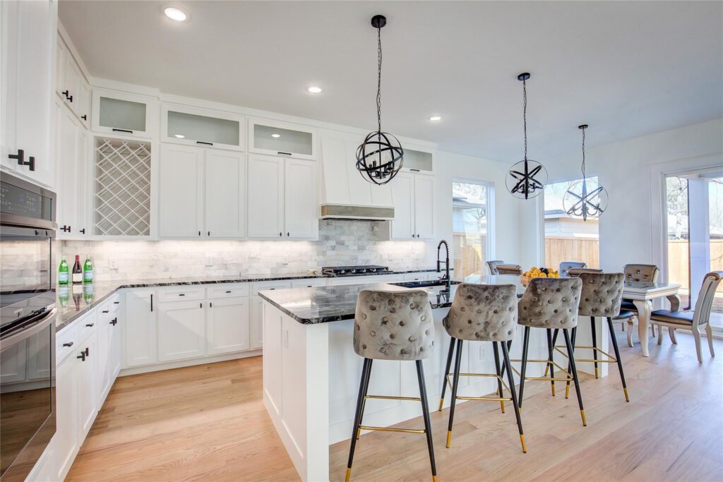 Bright modern kitchen with white cabinetry and a large island with floral bar stools.