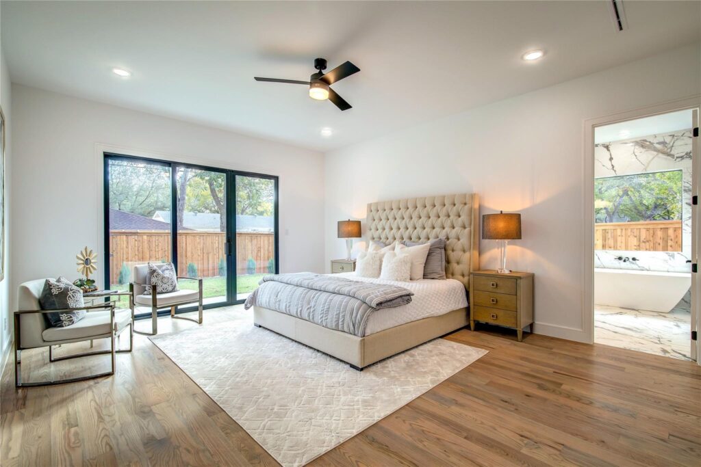 Elegant bedroom with tufted bed and large sliding glass doors.